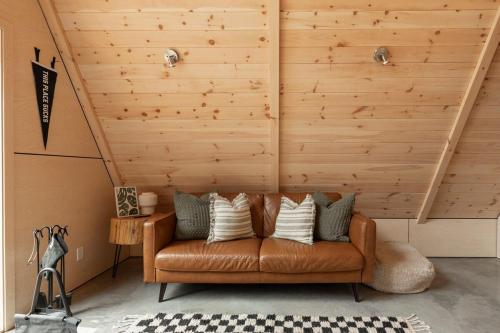 a brown leather couch in a room with wooden walls at Canadian Classic - Spa - Sauna - Fire - Forest in Val-David