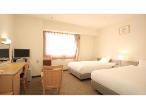 a hotel room with two beds and a desk at Smile Hotel Hirosaki - Vacation STAY 40511v in Hirosaki