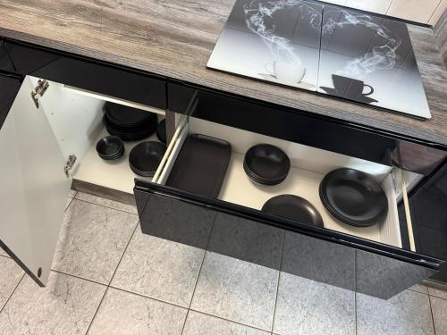 a drawer in a cabinet with black bowls and cups at Usedom Suite Zeitlos - 100 Meter zum Strand in Ostseebad Koserow