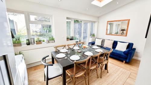 a dining room with a table and chairs and a couch at Lovely 4-Bedroom Kilburn Flat with Garden and Parking near Hampstead Heath, Abbey Road in London