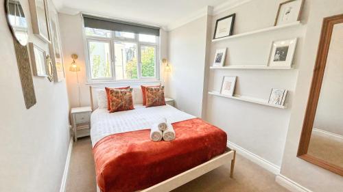a small bedroom with a bed and a window at Lovely 4-Bedroom Kilburn Flat with Garden and Parking near Hampstead Heath, Abbey Road by Staylio London in London