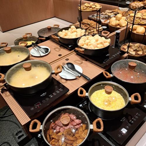 a table with pots and pans of food on a stove at L´acordes Hotel in Porto Velho