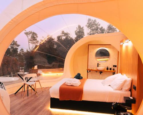 a bedroom with a large window with a bed and a table at Glamping Balú in Monesterio