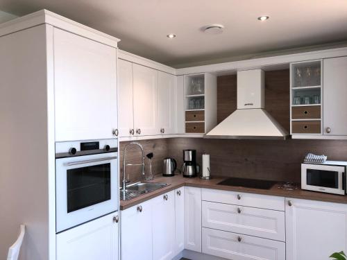 a white kitchen with white cabinets and a sink at Stora älg -Ferienhaus am Älgsjön in Arvika