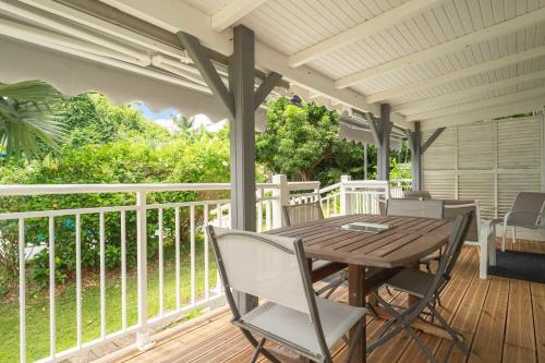 a porch with a wooden table and chairs at Appartement Iris in Sainte-Anne