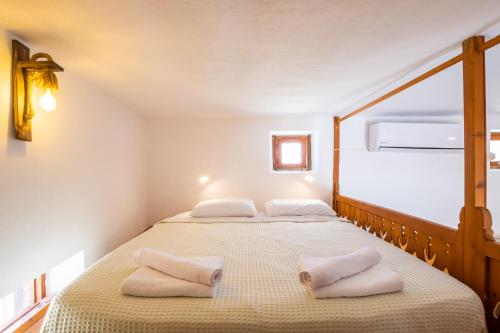 two beds in a small room with two towels at Constantino Traditional Retreat - 19th century residence in Karpathos Town