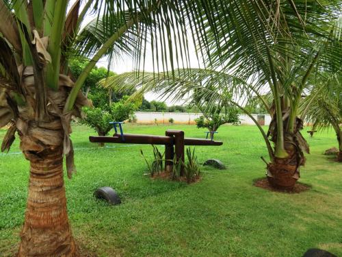 a bench next to two palm trees in a field at Pongsin Resort in Khun Han