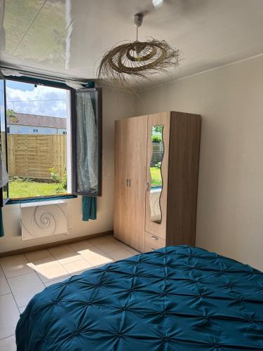 une chambre avec un lit bleu et une fenêtre dans l'établissement Chez Sylviane Rez-de-Chaussée 200 m de la mer, à Luc-sur-Mer