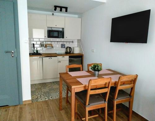 a kitchen with a table and chairs and a television at Melodia Ciszy Apartament Dębina in Debina