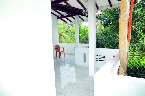 a white porch with a chair and plants at Sun Shades View Residence in Andugoda