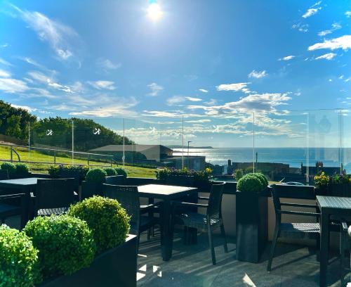 a patio with tables and chairs and a view of the ocean at The Knowes Hotel & Restaurant in Macduff