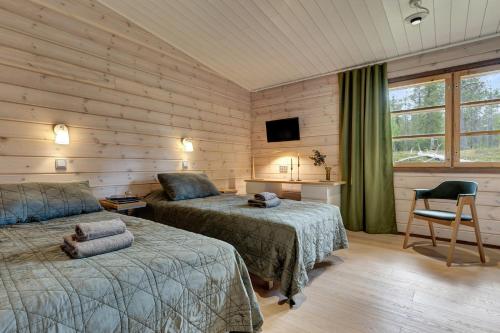 a bedroom with two beds and a tv and a chair at Lapland Fellas - Äkäslompolo in Äkäslompolo