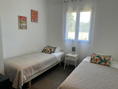a bedroom with two beds and a window at Villa Roccapina - Porto-Vecchio in Sotta