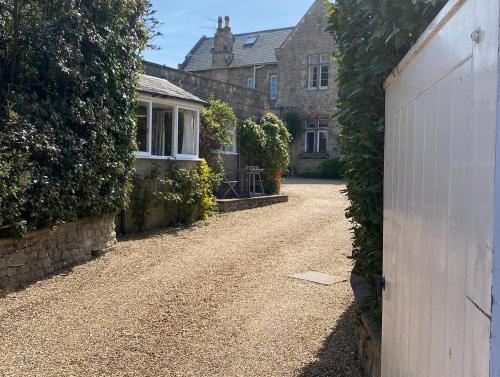 a driveway leading to a house with a white fence at The Cottage, ground floor property near the beach in Seaview