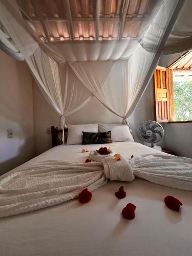 a bedroom with red roses on the bed at Chalé Vila Jasmim Caraíva bahia in Caraíva