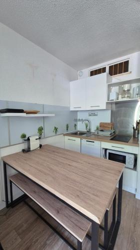 une cuisine avec une table en bois au milieu dans l'établissement AU VAL BENOÎT chez sylvain, à Allos