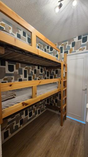 une chambre avec des lits superposés en bois avec un mur de carrelage dans l'établissement AU VAL BENOÎT chez sylvain, à Allos