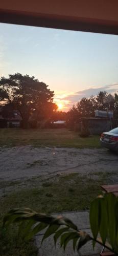 a sunset in a field with a car parked at Zofiówka in Pozezdrze