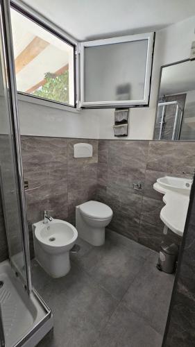 a bathroom with two sinks and a toilet and a window at Villa Dependance in Taranto