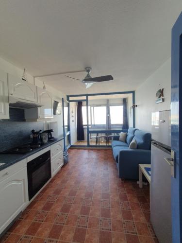 Il comprend une cuisine et un salon doté d'un canapé bleu. dans l'établissement Studio vue Mer Ile des Pêcheurs, au Cap d'Agde