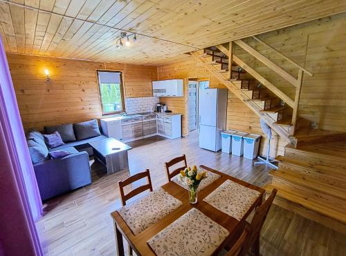 a living room with a dining table and a kitchen at Domki Apartamenty Ewelka in Okuninka