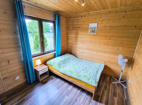 a small bedroom with a bed and a window at Domki Apartamenty Ewelka in Okuninka