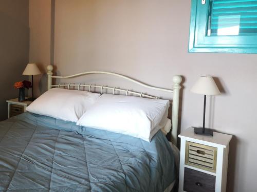 a bedroom with a bed and two night stands and a window at The Iconpainter Peroulia Villa in Kómboi