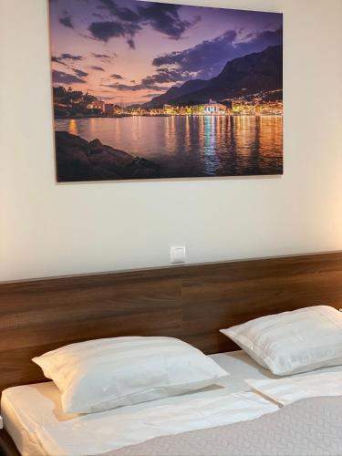 a bedroom with a bed with a picture on the wall at Gabrijel Apartments Makarska 2 in Makarska