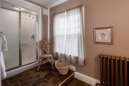 a bathroom with a shower and a chair next to a window at Jeddore Lodge in Head of Jeddore