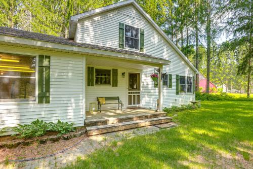 a white house with a porch with a bench on it at Less Than 1 Mi to ATV Trails Cadillac Golf Retreat! in Cadillac