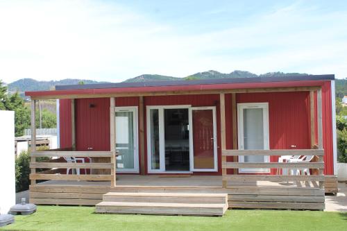 a red tiny house with a porch and two chairs at Padel Camp House in Cascais