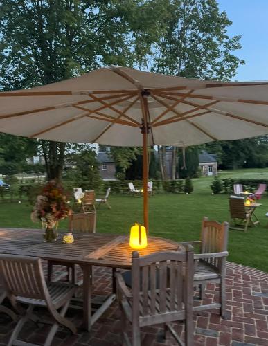 a wooden table with an umbrella on a patio at Manoir de Daubeuf in Daubeuf-Serville
