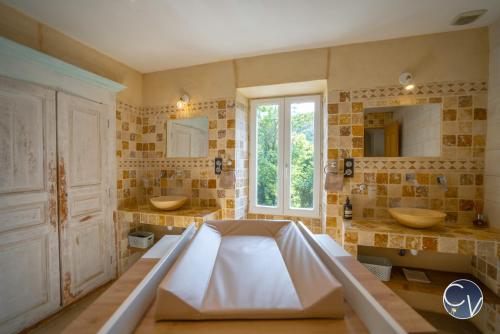 ein großes Badezimmer mit zwei Waschbecken und einer großen Badewanne in der Unterkunft Mas des Glycines in Saint-Montan