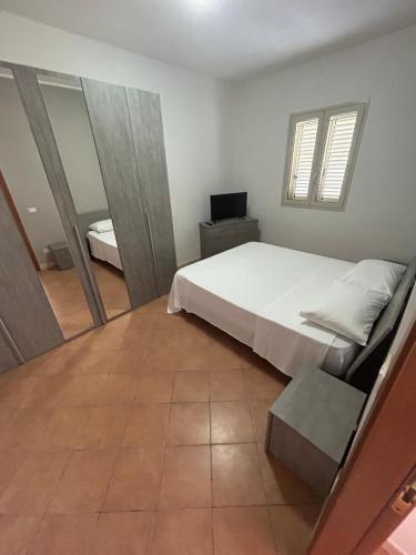 a bedroom with a white bed and a mirror at Villa acqua e sale in Santa Maria Del Focallo