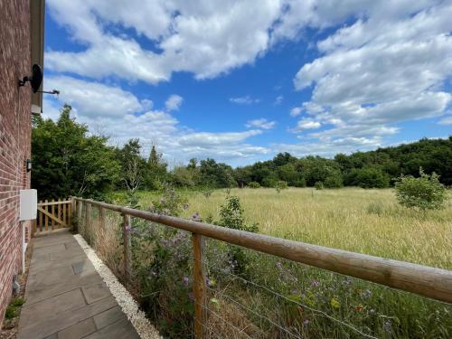 a wooden walkway to a field with a fence at 8 Iris Cottage, Coastal Hideaway - Suffolk in Wenhaston