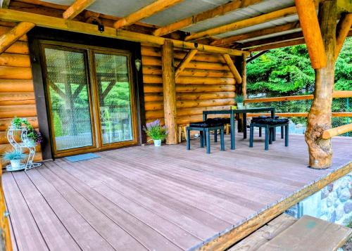 a porch of a log cabin with tables and chairs at Dom z Bala nad Cieminem in Jeleń