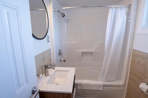 a white bathroom with a sink and a tub at Riôtel Carleton-sur-Mer in Carleton sur Mer