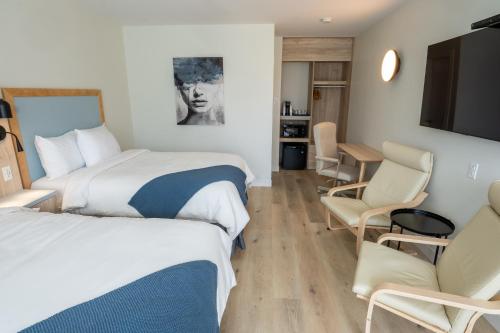 a hotel room with two beds and a table and chairs at Riôtel Carleton-sur-Mer in Carleton sur Mer