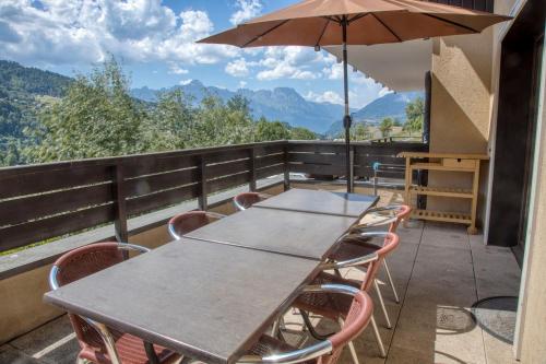 une table et des chaises sur un balcon avec un parasol dans l'établissement Duplex familial - Piscine intérieure, à Saint-Gervais-les-Bains