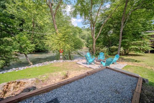a backyard with chairs and a table and a river at Riverfront Home w Gameroom & Screened Porch in Ellijay