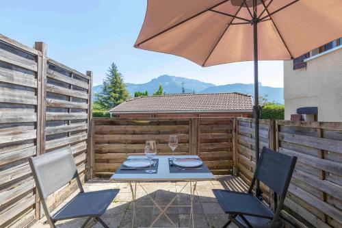 a patio with a table and an umbrella at Cabana & Studio Alpin Annecy - Terrasse Parking in Argonay