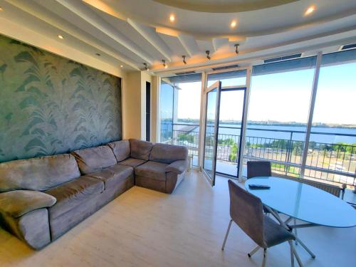a living room with a couch and a table at Семейные апартаменты в Мост Сити зал и 1 спальня, вид на реку, балкон Ванна in Dnipro