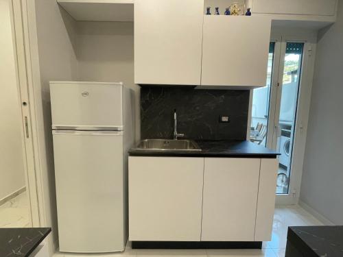 a white kitchen with a sink and a refrigerator at Alloggio comodo a Rapallo - Vicino al Mare in Rapallo