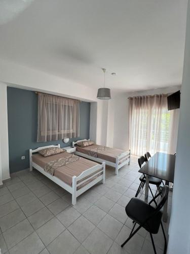 a bedroom with two beds and a table at Blue Sky Apartments 3 in Hanioti