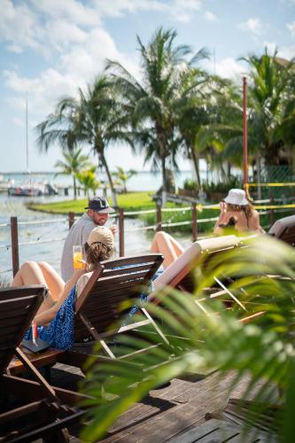 a group of people sitting in chairs on the beach at The Yak Lake House - Hostal Bacalar in Bacalar