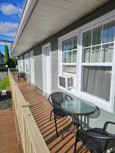 a porch with a table and chairs on a house at Motel de l'Outlet in Magog-Orford
