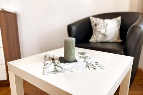 a candle on a white table with a chair at DC Room Luca in Zeltweg