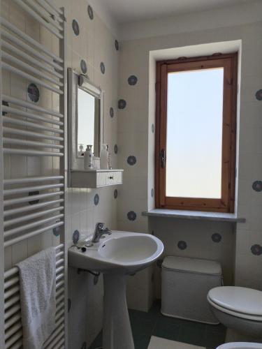 a bathroom with a sink and a toilet and a window at Castori 1 in Prazzo