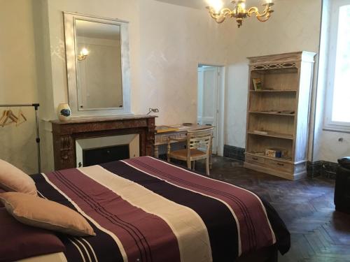 a bedroom with a bed and a desk and a mirror at Le Chai de Montaigne in Montcaret