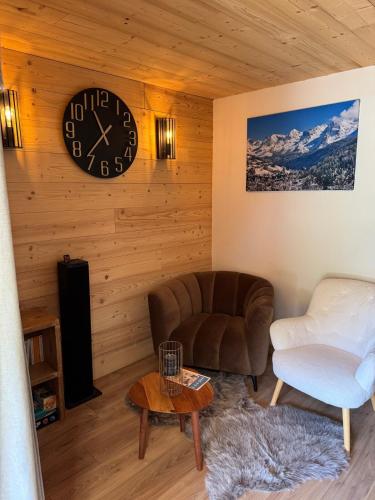 un salon avec un canapé et une horloge au mur dans l'établissement Le chalet des rêves - La Roche Blanche, à Entremont